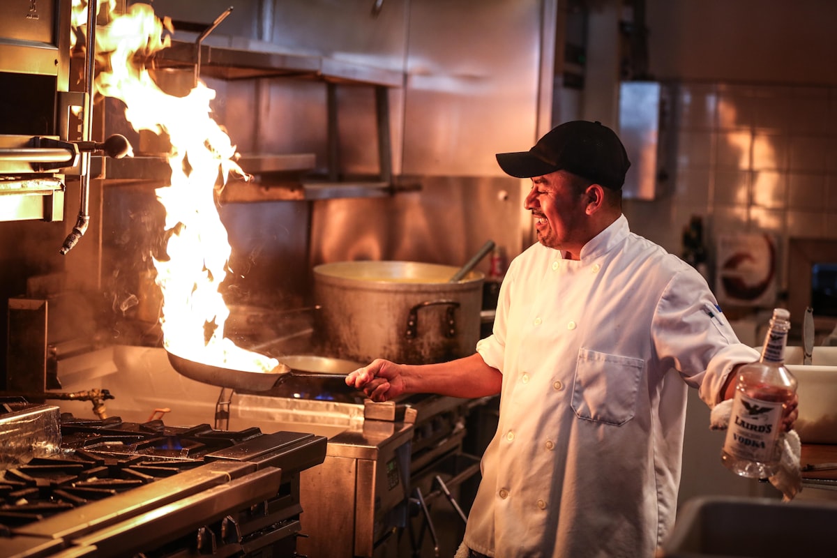 Restaurant kitchen manager cooking with open flame on a commercial stove